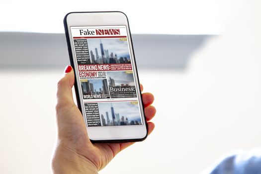 A female holding a smart phone reading fake news