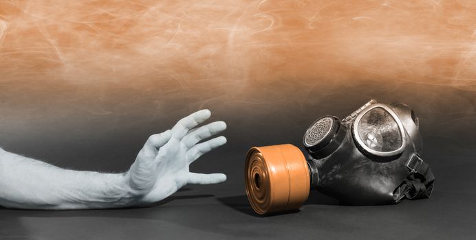 Man in room filled with smoke, trying to reach for vintage gasmask - Isolated on black - Orange smoke