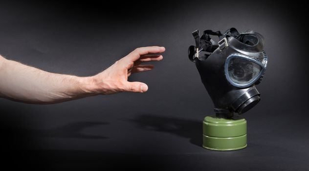 Man in room, trying to reach for vintage gasmask - Isolated on black - Green filter