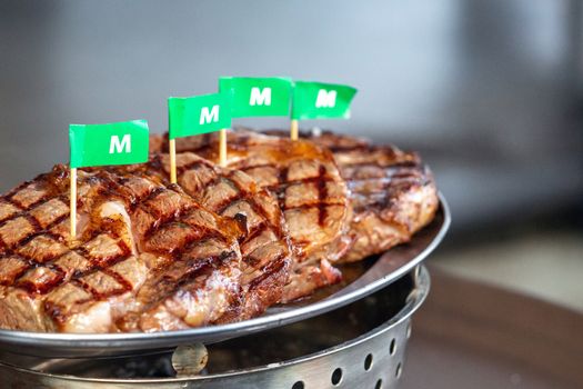 Grilled striploin steak arranged in a metal tray. Embroidered the green flag with the letter M. means medium cooked.