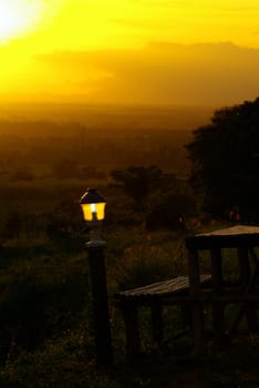 Natural wooden seats in the mountains in the light of the lantern and sunset