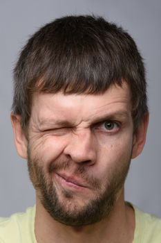 Close-up portrait of a man of European appearance who squeezed his left eye tightly