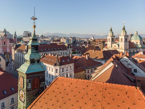 Scenic panoramic aerial drone view of rooftops of medieval city center, town hall and cathedral church in Ljubljana, capital of Slovenia, at sunset.