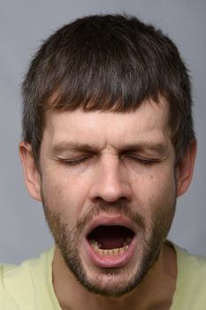 Close-up portrait of a yawning man of European appearance