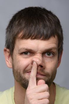 Portrait of a man of European appearance, who put his finger in his nose, close-up