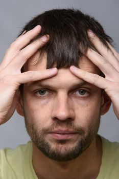 Close-up portrait of a man of European appearance clutching his head with his hands