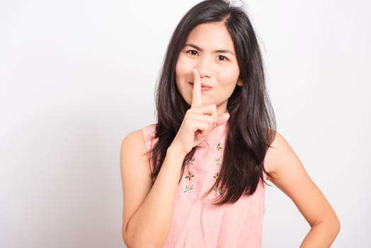 Portrait Asian beautiful young woman standing making hush gesture with fingers and looking to camera, shoot the photo in a studio on a white background, There was copys pace