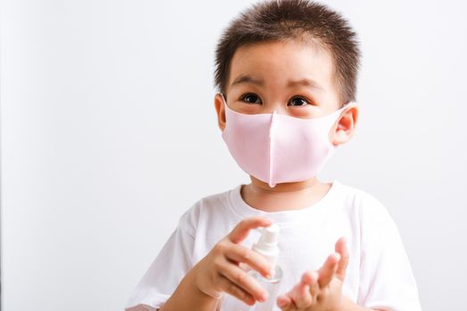 Closeup portrait Asian little child boy holding show bottle pump dispenser sanitizer alcohol spray hand wash cleaning, COVID-19 or coronavirus protection concept, isolated on white background