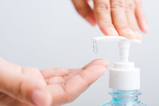 Close up Asian young woman applying press dispenser sanitizer alcohol gel pump to hand wash cleaning, hygiene prevention COVID-19 or coronavirus protection concept, isolated on white background