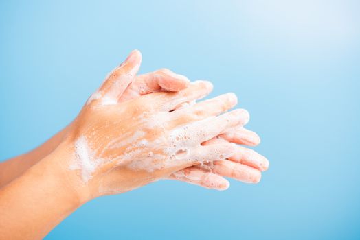 Closeup body care Asian young woman washing hands with soap have foam, hygiene prevention COVID-19 or coronavirus protection concept, isolated on blue background