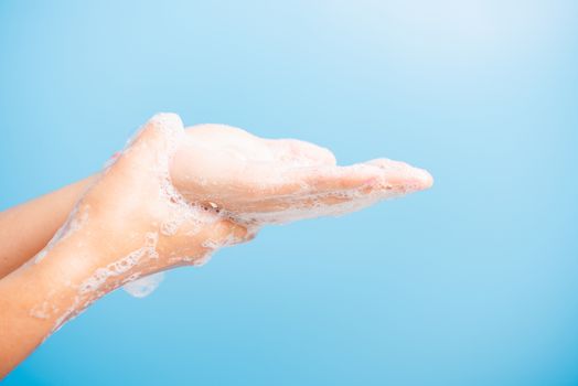 Closeup body care Asian young woman washing hands with soap have foam, hygiene prevention COVID-19 or coronavirus protection concept, isolated on blue background