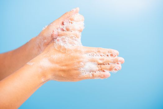 Closeup body care Asian young woman washing hands with soap have foam, hygiene prevention COVID-19 or coronavirus protection concept, isolated on blue background