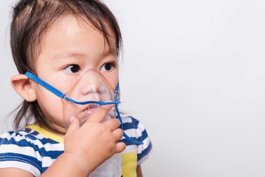 Closeup Asian face, Little baby girl sick her using steam inhaler nebulizer mask inhalation oneself on white background with copy space, health medical care