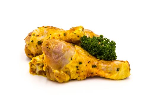 Chicken drumsticks marinate with parsley on a white background