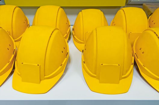 Yellow protecting hard hats on bench ready for workers to pick them.