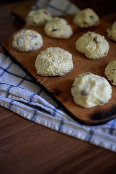 On the board prepared for frying Russian traditional home-made cottage cheese pancakes with raisins - cheesecakes on a wooden table.