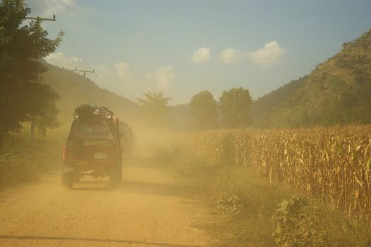 KANCHANABURI THAILAND - MAY 14 : Unidentified men driving Suzuki Sporty and Suzuki Caribien in the convoy touring caravans on May 14,2006  through the corn fields along the gravel road, Kanchanaburi, Thailand.