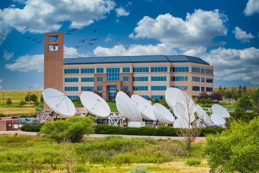 An array of satellite dishes outside a brick and glass building