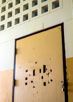 Many broken holes on the old classroom door are locked