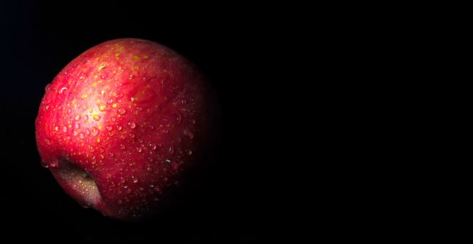 Close-up of Water droplet on glossy surface of freshness red apple on black background