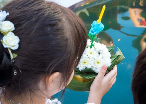 A girl raises her decorated float for prayer at the Loi Krathong festival