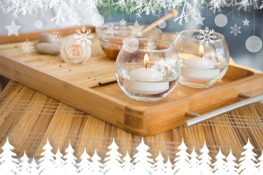 Candles and beauty treatment on tray against fir tree forest and snowflakes