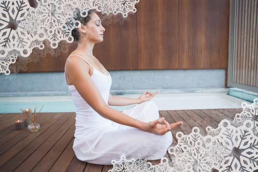Peaceful brunette in white sitting in lotus pose  against snowflake frame