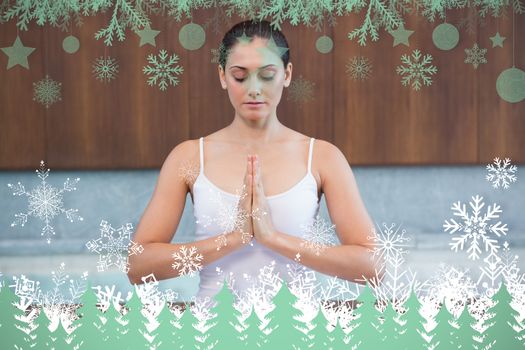 Peaceful woman in white sitting in lotus pose against snowflakes and fir trees in green