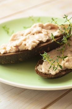 sandwiches with homemade chicken liver pate for breakfast on green plate and wooden table