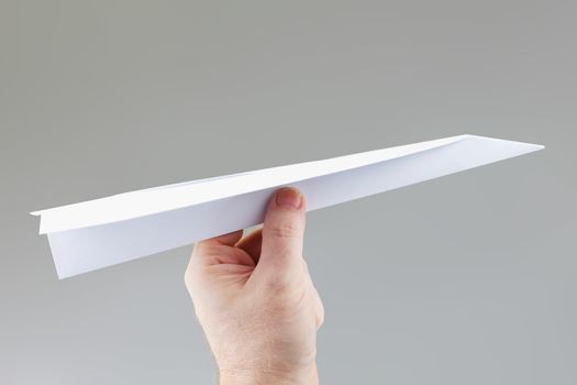 A hand holding a paper dart plane ready to throw