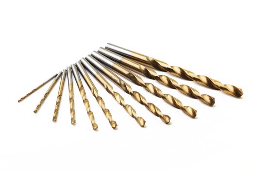 A set of ten drill bits on white with selective focus