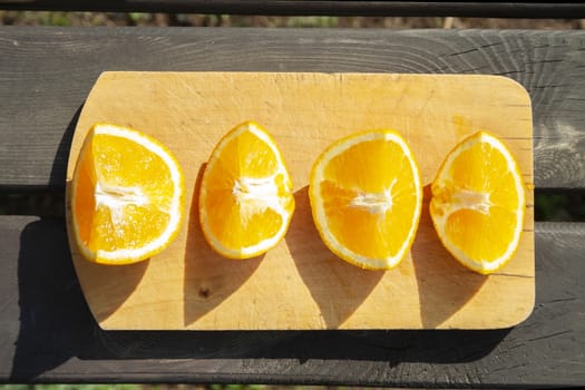 appetizing cutted pieces of orange fruit on cutting board on wooden brown table on sun lights. healthy eating, fruits, summer top view