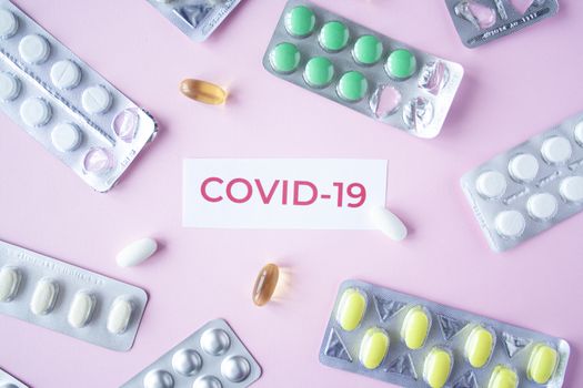 The inscription quote covid-19 on a pink background with many clusters of pills and pills. Coronavirus treatment concept. Medicines, vaccine for the virus. Antibiotics