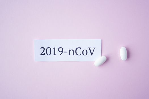 The inscription quote 2019 ncov on a blue background with two white tablets next to it. Coronavirus treatment concept. Medicines, vaccine for the virus.