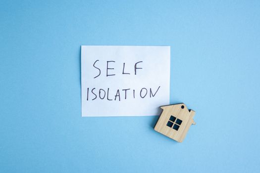 The inscription on a white sheet quote self isolation with small wooden house trinket. The concept of self-isolation. Coronavirus, stop the spread of infection. 2019-ncov