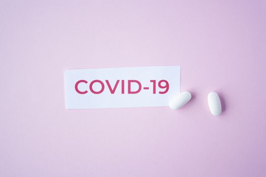 The inscription quote covid-19 on a blue background with two white tablets next to it. Coronavirus treatment concept. Medicines, vaccine for the virus.