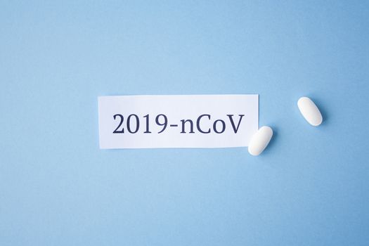 The inscription quote 2019 ncov on a blue background with two white tablets next to it. Coronavirus treatment concept. Medicines, vaccine for the virus.