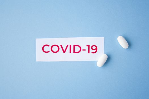 The inscription quote covid-19 on a blue background with two white tablets next to it. Coronavirus treatment concept. Medicines, vaccine for the virus.