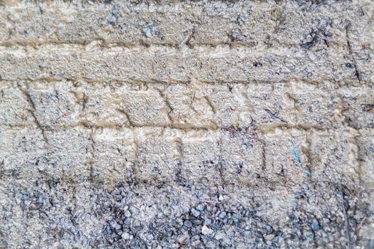 In a rural parking area filled with small gravel, tire tracks are seen impressed in the mud on a wet day.