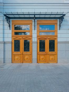 Two huge wooden doors with sky reflections in windows