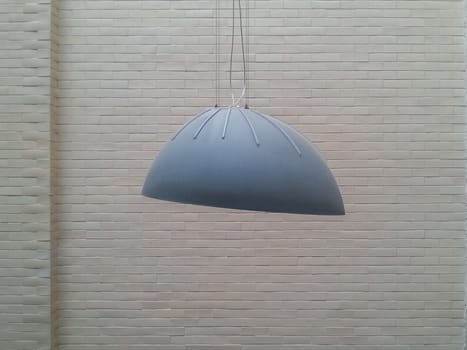 Gray huge lamp in front of white brick wall