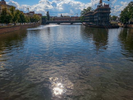 Sun reflecting in river in Wroclaw with city in background