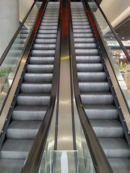 Symmetric escalator to darkness inside shopping mall