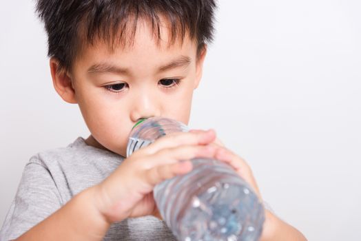 Closeup Asian face, Little children boy drinking water from Plastic bottle on white background with copy space, health medical care
