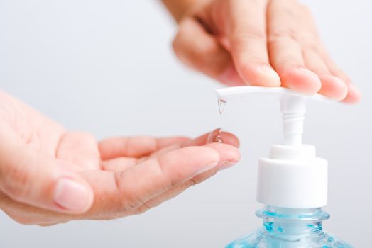Close up Asian young woman applying press dispenser sanitizer alcohol gel pump to hand wash cleaning, hygiene prevention COVID-19 or coronavirus protection concept, isolated on white background