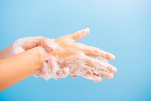 Closeup body care Asian young woman washing hands with soap have foam, hygiene prevention COVID-19 or coronavirus protection concept, isolated on blue background