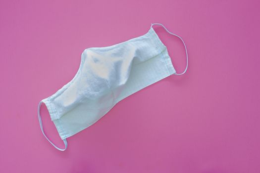 White homemade face mask for adults on a pink background