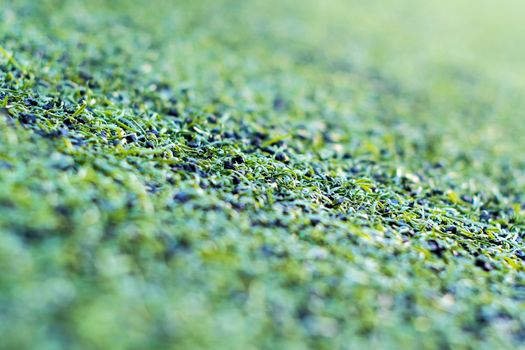 Texture of plastic artificial grass and the rubber pellets on school yard