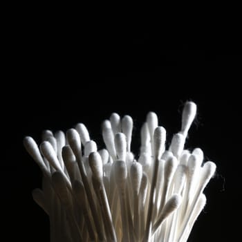 container of cotton buds in backlight on a black background