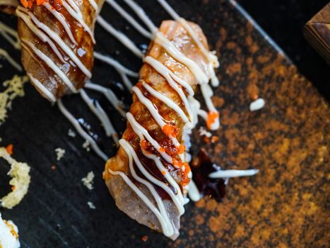 Seared wagyu beef sushi topped with mayonnaise and ebiko served on a black stone dish. Japanese Cuisine Buffet.